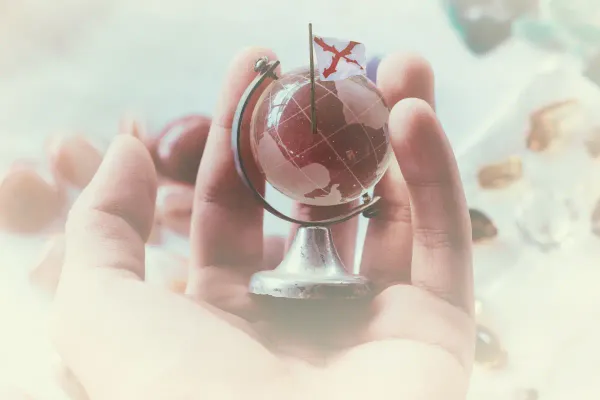 man with a glass globe in his hand with a flag stuck into it