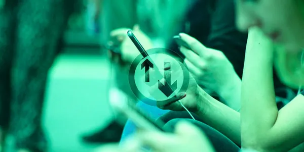 A closeup photo of a few people leaning over fixated on their phones. Overlaid on the photo is a icon with up and down arrows.
