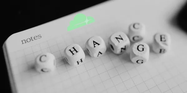 a notebook has a series of block with letter on them arranged to spell the word change. the cloudflare logo is overlaid on it.