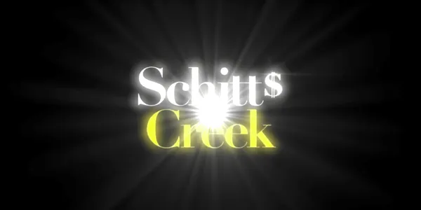 The Schitts Creek title card is illuminated with a dazzling light. The font used for the title is a serif font. The last s in the first word is modified to look like a dollar sign.