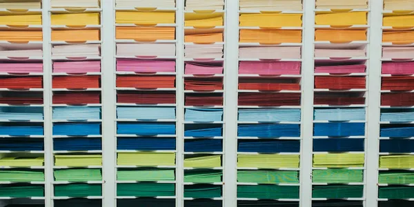 A pigeon-holed style series of boxes houses collections of coloured paper